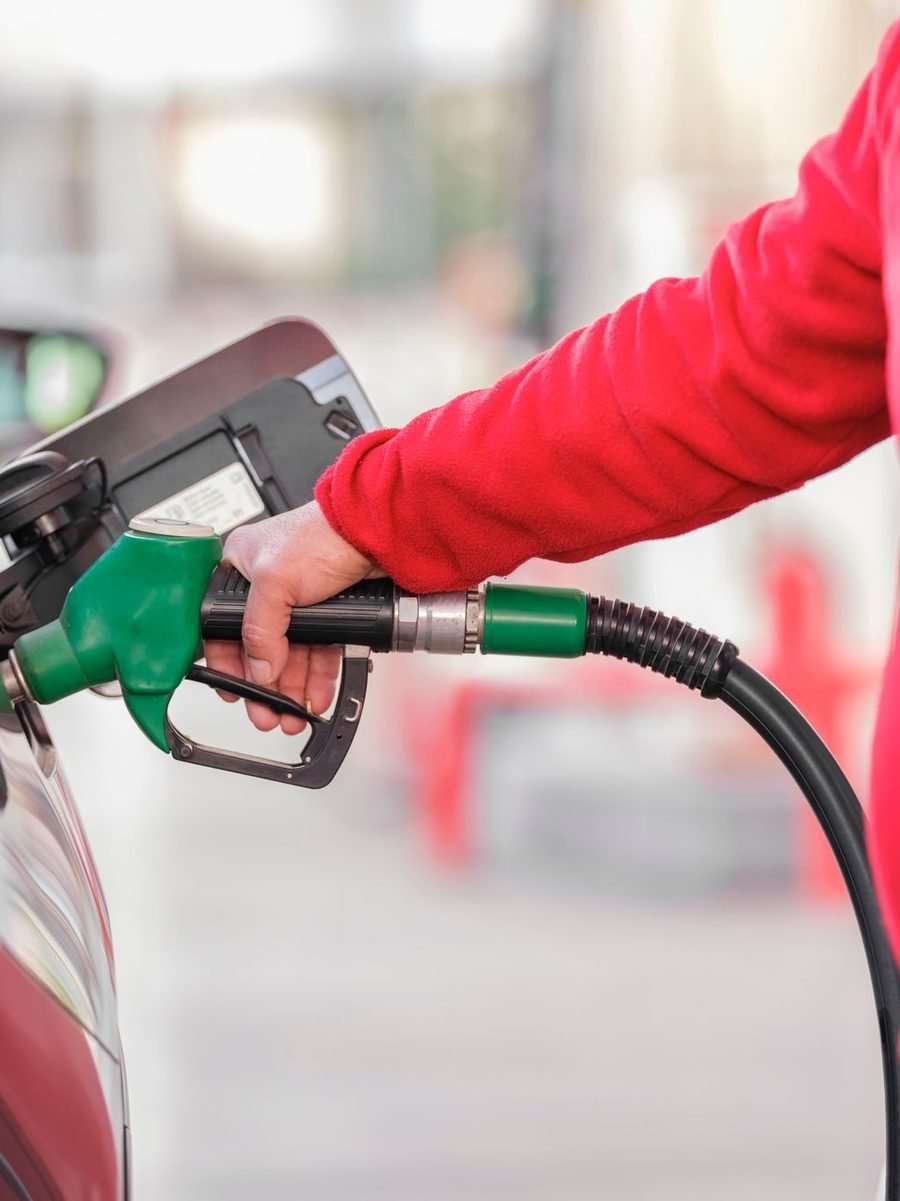 Attendant in a red jacket refuelling a car