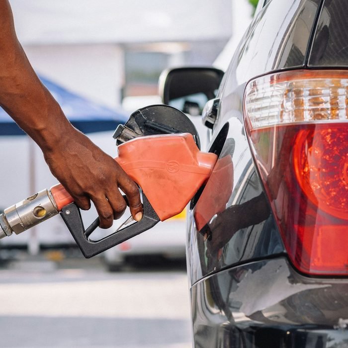 Attendant refuelling a car with an orange nozzle