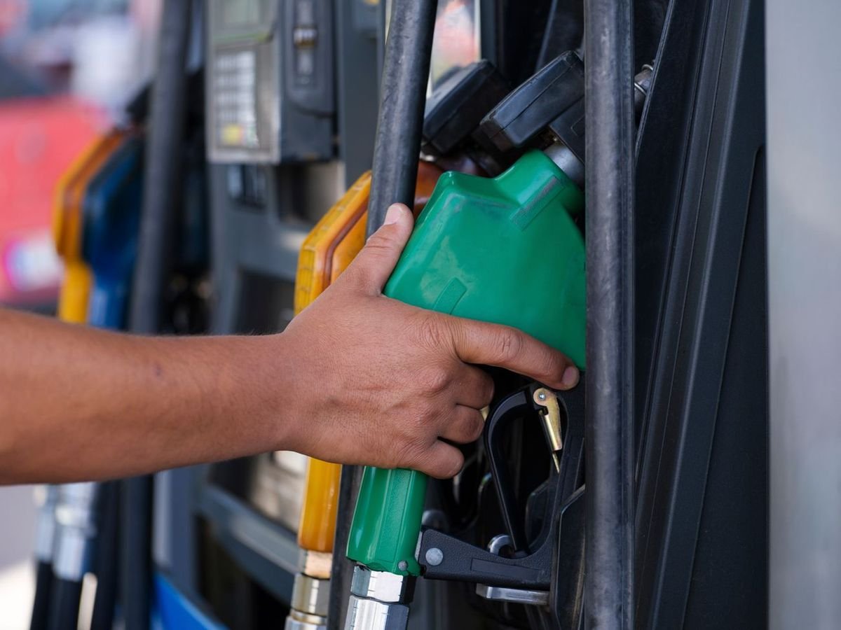 Attendant holding a fuel nozzle at a dispenser